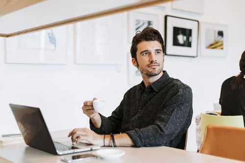 Man drinking coffee while working
